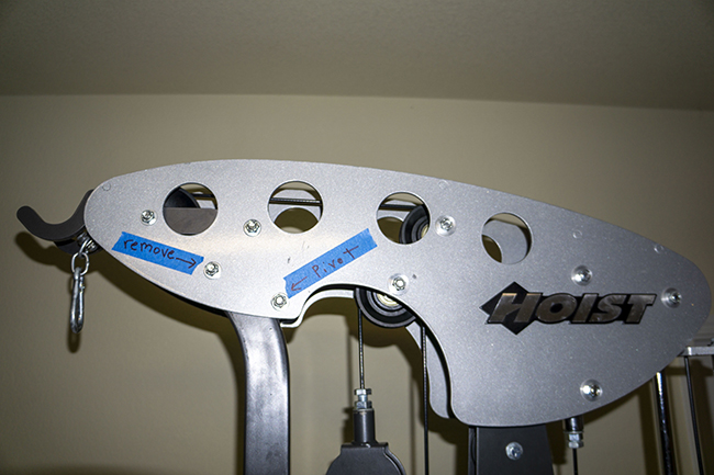 Photograph of Hoist Fitness V5 vertical gym top mainframe assembly and the two bolts necessary to pivot it up for weight plate removal.